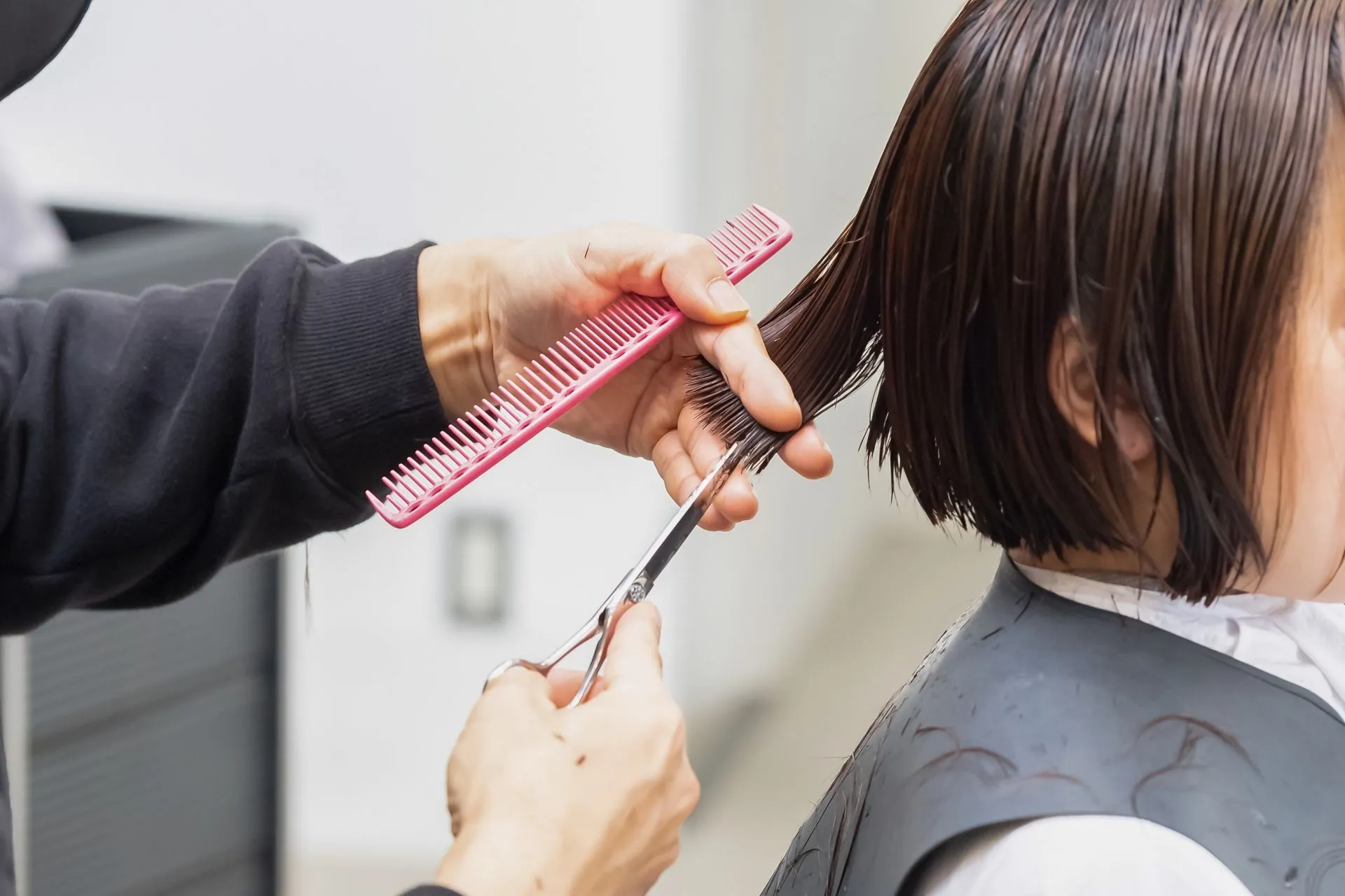 美容師がボブヘアをカットしている様子